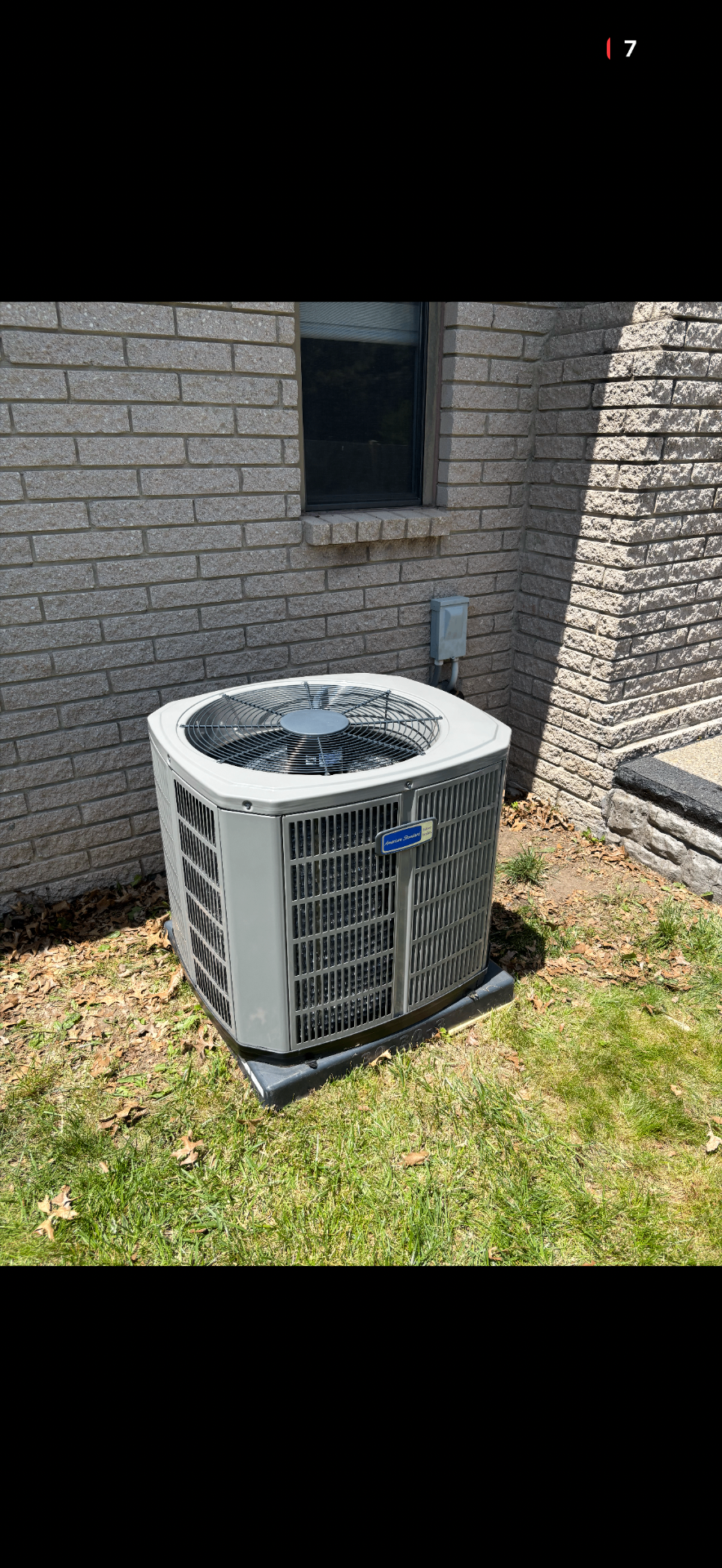 Outdoor residential condenser unit installed beside home — overview